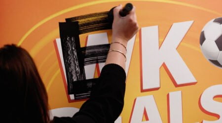 Iemand tekent met een viltstift een E op de plek waar de W staat.