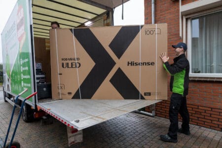 Een jongen tilt een Hisense tv uit een vrachtwagen.