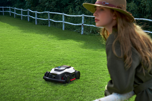 Een robotmaaier van Dreame. In de hoek staat een vrouw.